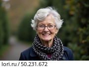 A cheerful elderly woman smiles warmly while strolling along a pathway lined with trees, wrapped in a cozy scarf, enjoying the serene autumn atmosphere Generative AI. Стоковое AI-изображение, AI-художник Юлия Петровская / Фотобанк Лори