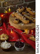 Cereal bars with almonds, coconut and cranberries on a Christmas season table decorated with lights. Стоковое фото, агентство Ingram Publishing / Фотобанк Лори