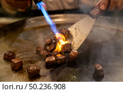 Cooking of beef teppanyaki recipe japanese grilled beef on cooking pan with scraper and gas burner flame. Стоковое фото, агентство Ingram Publishing / Фотобанк Лори