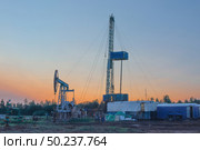 Drilling a well in an oil field. In the foreground is a mobile drilling rig. In the background, oil production at the field using a rocking machine. Summer. Beautiful sky and nature. Стоковое фото, фотограф Владимир Ендовицкий / Фотобанк Лори