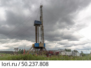 Drilling a well in an oil field. In the foreground is a mobile drilling rig. In the background, oil production at the field using a rocking machine. Summer. Beautiful sky and nature. Стоковое фото, фотограф Владимир Ендовицкий / Фотобанк Лори