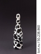 Creative painted wine bottle white with dark spots on a black background, copy space. Minimalism concept.. Holiday painted wine bottle with black spots on a dark gray. Стоковое фото, агентство Ingram Publishing / Фотобанк Лори