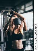 Athletic fitness woman pumping up muscles with dumbbells, Fit woman working out with trainer at the gym. Стоковое фото, агентство Ingram Publishing / Фотобанк Лори