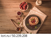 Pancakes with raspberries, banana slices, pomegranate seeds and honey on wooden vintage table. Стоковое фото, агентство Ingram Publishing / Фотобанк Лори