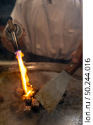 Cooking of beef teppanyaki recipe japanese grilled beef on cooking pan with scraper and gas burner flame. Стоковое фото, агентство Ingram Publishing / Фотобанк Лори