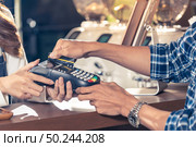 Close-up of asian customer using his credit card to swipe with EDC to pay a barista for his coffee purchase at a cafe bar. Стоковое фото, агентство Ingram Publishing / Фотобанк Лори
