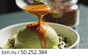 A close-up of a spoon swirling a fusion dessert miso caramel over matcha ice cream with a dusting of black sesame seeds, concept of unusual meal and food. Стоковое AI-видео, аниматор Sergey Grishin / Фотобанк Лори