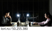 Young adult asian businessman and woman working late at night in their office with desktop computer and laptop. Using as hard working and working late concept. Стоковое фото, агентство Ingram Publishing / Фотобанк Лори