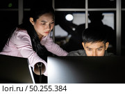 Young adult asian businessman dicuss with collegue about work late at night in their office with desktop computer. Using as hard working and working late concept. Стоковое фото, агентство Ingram Publishing / Фотобанк Лори