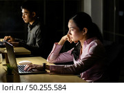 Young adult asian businessman and woman working late at night in their office with desktop computer and laptop. Using as hard working and working late concept. Стоковое фото, агентство Ingram Publishing / Фотобанк Лори