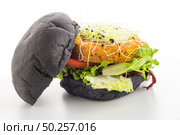 Tasty grilled veggie burger with chickpeas and vegetables on black bread on white background. Стоковое фото, агентство Ingram Publishing / Фотобанк Лори