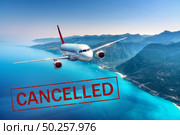 Airplane and flight cancellation. Canceled flights in Europe, Asia and USA airports. Travel cancelled. Pandemic of coronavirus. Fying passenger aircraft over the tropical sea coast with text. Covid-19. Стоковое фото, агентство Ingram Publishing / Фотобанк Лори