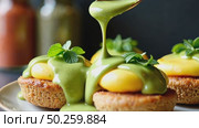 A close-up of a spoonful of matcha-infused hollandaise sauce drizzling over eggs Benedict, green and yellow hues contrasting beautiful kitchen background. Стоковое AI-видео, аниматор Sergey Grishin / Фотобанк Лори