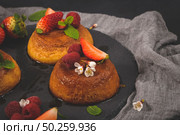Caramel custard puddings on round slate on and dark kitchen countertop. Стоковое фото, агентство Ingram Publishing / Фотобанк Лори