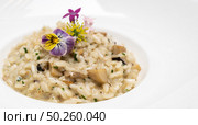 Creamy cheese risotto with mushroom and truffle oil decorate with yellow and purple flower. International italian gourmet cuisine a la carte in buffet live station. Using for food and drink industry.. Risotto. Стоковое фото, агентство Ingram Publishing / Фотобанк Лори