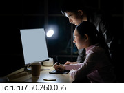 Young adult asian businessman dicuss with collegue about work late at night in their office with desktop computer. Using as hard working and working late concept. Стоковое фото, агентство Ingram Publishing / Фотобанк Лори