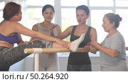 Group of cheerful relaxed women of different ages casually socializing and stretching at ballet barre after dance practice in amateur choreographic studio. Стоковое видео, видеограф Яков Филимонов / Фотобанк Лори