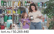 Woman with child family selects and studies label makeup cosmetic agent. Стоковое видео, видеограф Яков Филимонов / Фотобанк Лори