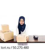 E-Commerce asian muslim women merchant work from home on wooden table with postal parcel cardboard boxes for shipping orders. Studio shot on white background for Selling online and small business SME. Стоковое фото, агентство Ingram Publishing / Фотобанк Лори