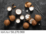 Coconut milk, whole and cracked coconuts on black background, top view. Стоковое фото, агентство Ingram Publishing / Фотобанк Лори