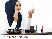 Young Muslim woman hold cosmetic and looking to camera to review product as vlog and blogger on white background taken in studio. Using for Fashion and beauty concept. Стоковое фото, агентство Ingram Publishing / Фотобанк Лори
