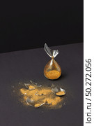 Brocken old-fashioned aged hourglass with bits of glass and golden sand on a duotone dark background with soft shadows, copy space.. Crashed outdated sandglass with golden sand on a black duotone background. Стоковое фото, агентство Ingram Publishing / Фотобанк Лори