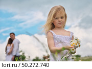 Little girl and his parents at blury background on camomile meadow at nature. Children pick flowers. Social and family problem. . Стоковое фото, агентство Ingram Publishing / Фотобанк Лори