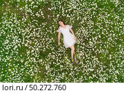 Beautiful girl lies in camomile daisy flower. View from above. Aerial photography. Стоковое фото, агентство Ingram Publishing / Фотобанк Лори