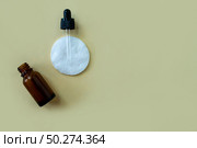 Flat lay bottle with a pipette and a cotton pad on a beige background. Стоковое фото, фотограф Юлия Николаева / Фотобанк Лори