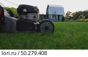 Woman with a lawn mower mowing a garden plot. Стоковое видео, видеограф Igor Skripachev / Фотобанк Лори
