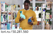 Before buying in household shop, African male customer choose glass cleaner spray. Стоковое видео, видеограф Яков Филимонов / Фотобанк Лори