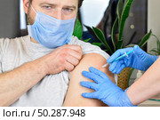 Man with face mask getting vaccinated, coronavirus, covid-19 and vaccination concept. Doctor giving antivirus injection to patient. Стоковое фото, фотограф Марина Демидюк / Фотобанк Лори