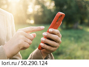 Brest, Belarus - 02 August 2022: Closeup of female hands using a smart phone, nature background. Unknown Woman using mobile phone in sunset outdoors. Unrecognizable person touching smartphone screen. Стоковое фото, фотограф Марина Демидюк / Фотобанк Лори