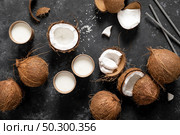 Coconut milk, whole and cracked coconuts on black background, top view. Стоковое фото, агентство Ingram Publishing / Фотобанк Лори