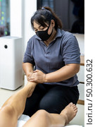 Quarantine asian woman do foot massage at home while city lockdown for social distance due to coronavirus pandemic. Massage and spa is one of service business that shutdown while city lockdown. Стоковое фото, агентство Ingram Publishing / Фотобанк Лори