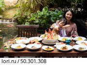Portrait of mom and daughtersit at garden of restaurant of lobster shrimp steak beef lamb pasta spaghetti risotto rice sushi sashimi and wine using for buffet food drink background. Стоковое фото, агентство Ingram Publishing / Фотобанк Лори