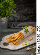 Fresh baked homemade grissini bread sticks in white ceramic tray with olive oil and basil herbs over kitchen counter top. Стоковое фото, агентство Ingram Publishing / Фотобанк Лори