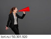 Business young woman speaking to a megaphone, over a grey background. Стоковое фото, агентство Ingram Publishing / Фотобанк Лори