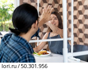 Asian young couple eating out together at new normal social distance restaurant with table shiled partition reduce infection of coronavirus covid-19 pandemic. Restaurant new normal lifestyle. Стоковое фото, агентство Ingram Publishing / Фотобанк Лори