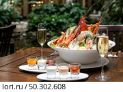 Bowl of gourmet fresh seafood on ice with savory sauce serve with white wine glass on vintage wooden table. Restaurant gastronomy food and drink consumerism concept. Стоковое фото, агентство Ingram Publishing / Фотобанк Лори