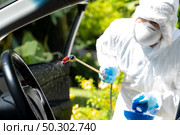 Close up of chemical alcohol spray cleaning inside car to disinfect and decontaminate coronavirus covid-19 by specialist cleaner wearing personal protective equipment PPE. New normal Hygiene concept. Стоковое фото, агентство Ingram Publishing / Фотобанк Лори