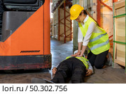 Asian worker do Cardiopulmonary Resuscitation CPR after warehouse manager lying down on warehouse floor after accident from forklift. Using for safety first and business insurance concept. Стоковое фото, агентство Ingram Publishing / Фотобанк Лори
