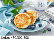 Cottage cheese pancakes, sweet curd fritters with berries, syrniki with honey and fresh blueberry on breakfast table. Стоковое фото, агентство Ingram Publishing / Фотобанк Лори
