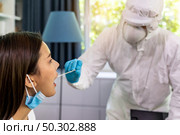Medical staff with PPE suit test coronavirus covid-19 to asian woman by throat swab at home. New normal healthcare service at home and medical delivery concept. Стоковое фото, агентство Ingram Publishing / Фотобанк Лори