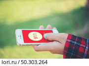 Woman holding a smartphone dialing emergency number on screen. Graphics make up on screen. Стоковое фото, агентство Ingram Publishing / Фотобанк Лори