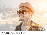 Young hipster man in earphones holding smartphone isolated on the white background. Стоковое фото, агентство Ingram Publishing / Фотобанк Лори