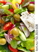Greek salad. Fresh vegetable salad of cucumbers, tomatoes, olives, onion, bell pepper, feta cheese, lettuce and herbs and dressed with salt, pepper and olive oil. Popular greek Horiatiki salad. Стоковое фото, агентство Ingram Publishing / Фотобанк Лори
