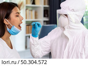 Medical staff with PPE suit test coronavirus covid-19 to asian woman by throat swab at home. New normal health care service at home and medical delivery and COVID-19 testing concept. Стоковое фото, агентство Ingram Publishing / Фотобанк Лори