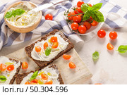 Rye bread bruschetta with cream cheese, olive oil and basil dip, cherry tomatoes, fresh basil leaves on wooden board. Стоковое фото, агентство Ingram Publishing / Фотобанк Лори