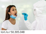 Medical staff with PPE suit test coronavirus covid-19 to asian woman by throat swab at home. New normal health care service at home and medical delivery and COVID-19 testing concept. Стоковое фото, агентство Ingram Publishing / Фотобанк Лори